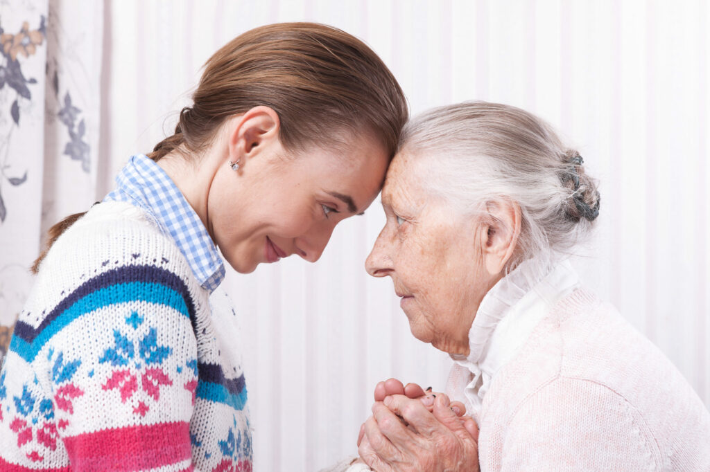 Helping hands, care for the elderly concept closeup. Senior and caregiver holding hands at home